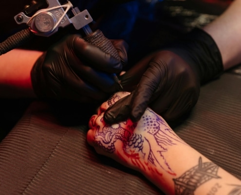 A tattoo artist uses a liner to begin the line work of a dragon tattoo. Such terms can be found in a tattoo dictionary.