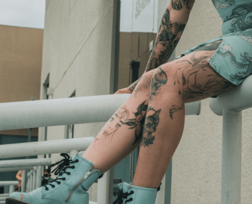 A woman in blue with many knee tattoos.