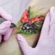 Color tattoo of a ladybug with bright red wings and black spots, detailed with realistic shading and fine linework